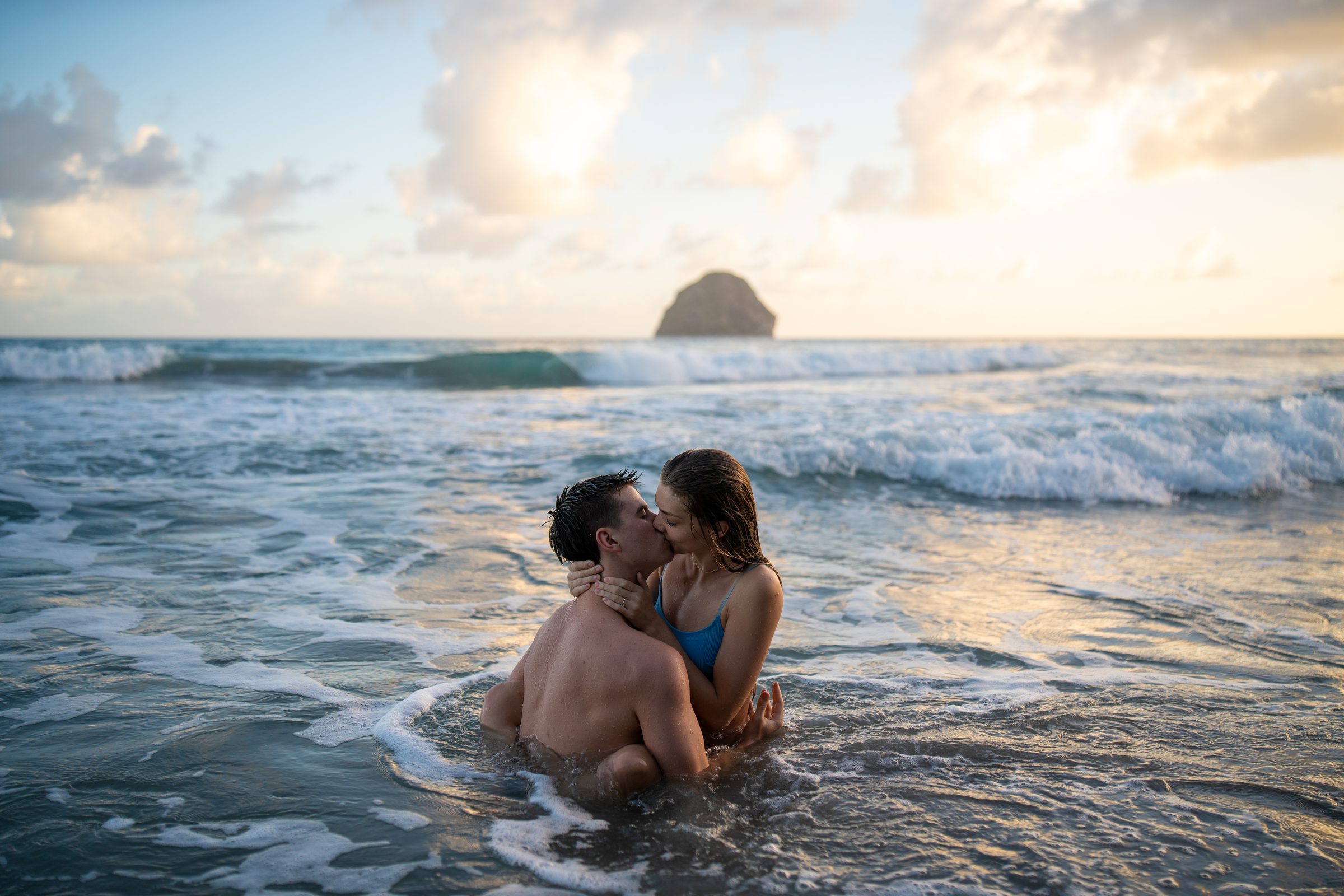 Couple enlacé dans les vagues au coucher du soleil, devant le rocher du Diamant